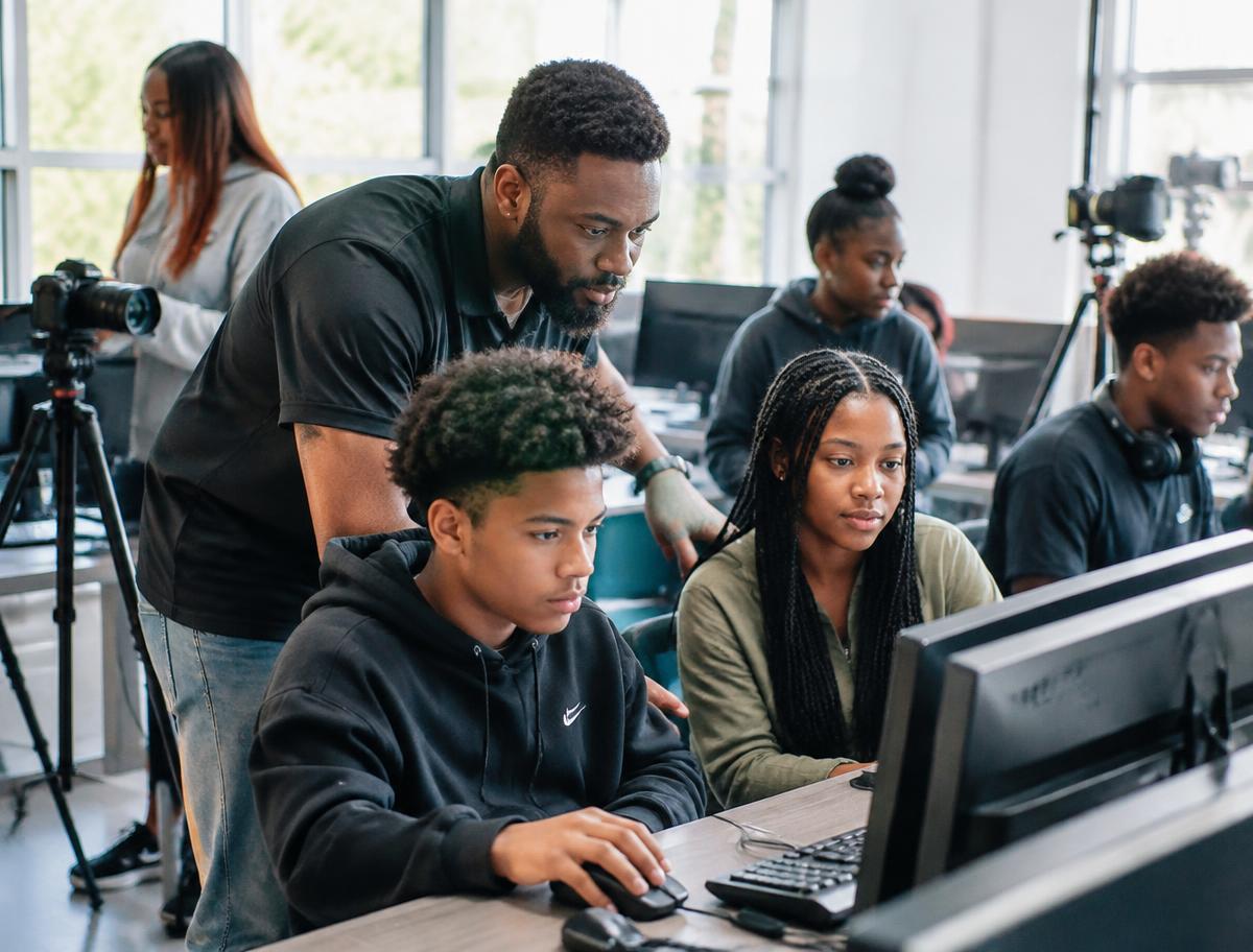 A mentor guiding a young person through a learning session